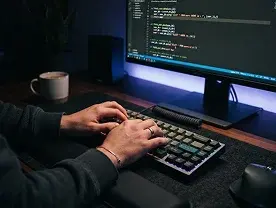 Code on a monitor in a dimly lit workspace